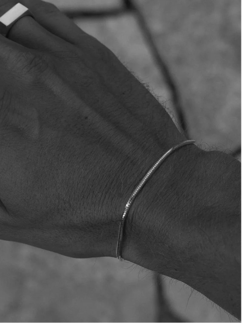 Man wearing minimalist silver bracelet featuring a square link design
