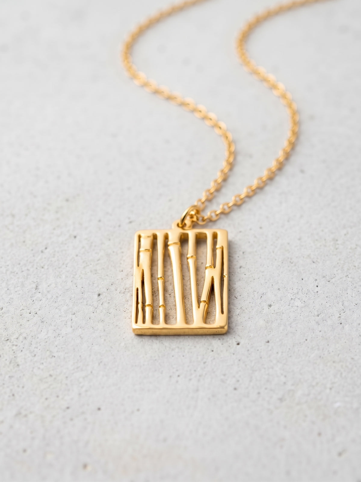 LOUVOND Abstract Pendant met rechthoekige goudkleurige hanger met verticale lijnen aan een fijne ketting.