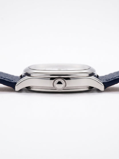 Zijaanzicht van het LOUVOND Lucien horloge met gepolijste zilverkleurige kast en marineblauwe lederen horlogeband.