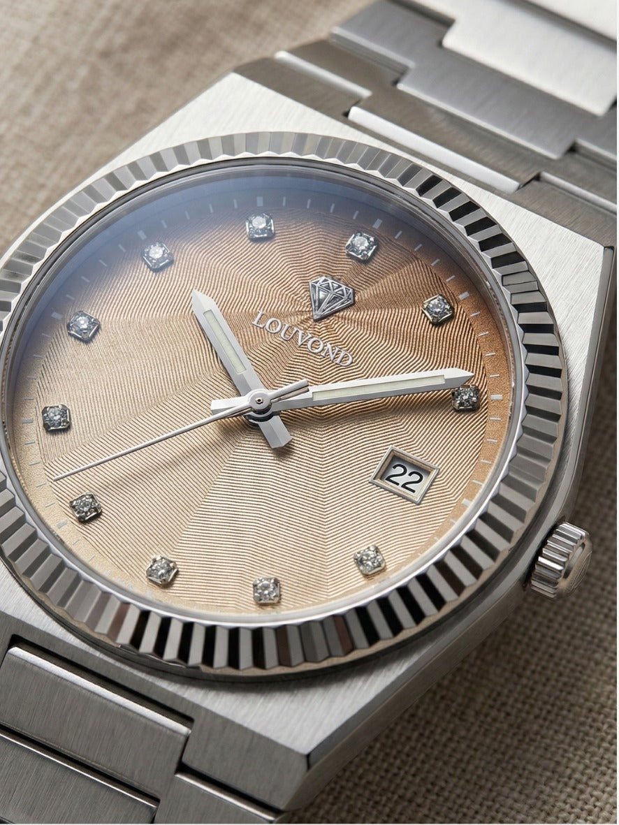 LOUVOND Monarch horloge met goudkleurige wijzerplaat, diamantindexen en geribbelde lunette in een zilveren kast.