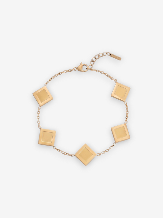 LOUVOND Prisma schakelarmband in goudkleur met vijf vierkante bedels op een lichte achtergrond