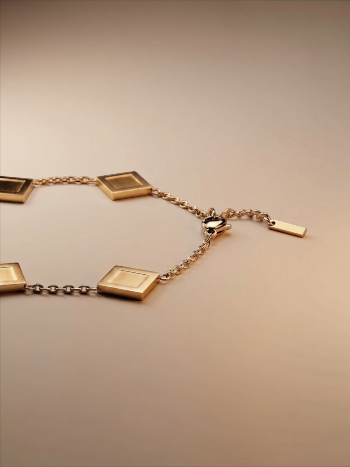 LOUVOND Prisma schakelarmband in goud met vierkante bedels op een zachte beige achtergrond.