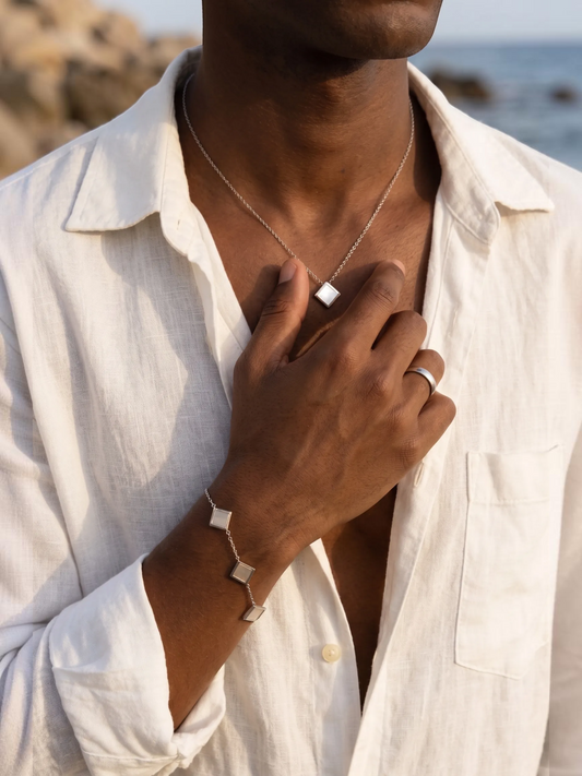 LOUVOND Prisma Link Pendant ketting met vierkante hanger en bijpassende armband in zilverkleur op een model.