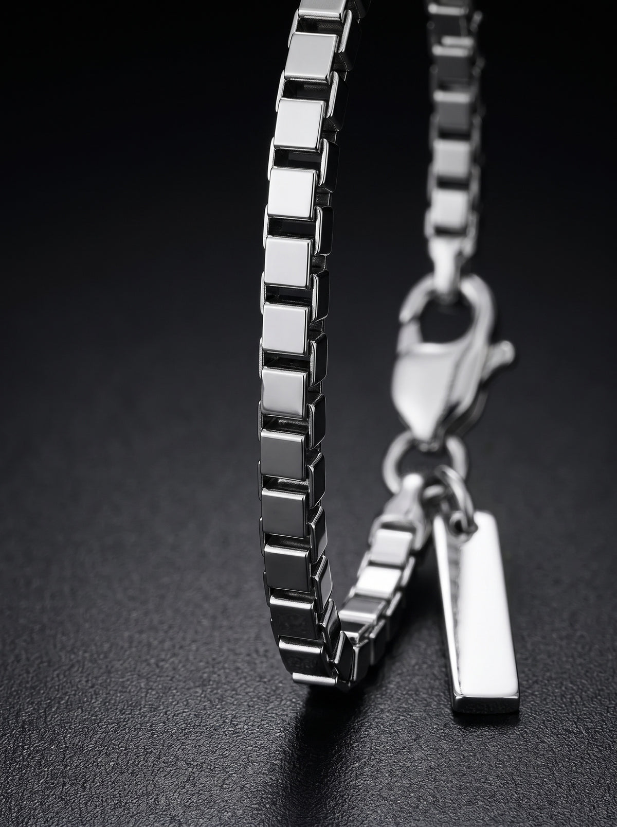 LOUVOND Revo armband met minimalistische vierkante schakels in glanzend zilverkleurig metaal op zwarte achtergrond