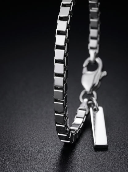 LOUVOND Revo armband met minimalistische vierkante schakels in glanzend zilverkleurig metaal op zwarte achtergrond